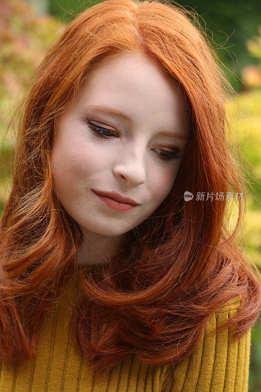 红发少女14 /15岁造型秋天的妆容，看向下远离相机，模糊的秋天的树叶颜色背景